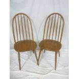 A set of four 1960's Ercol light elm dining chairs with spindle backs and polished seats on tapered
