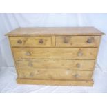 An old polished pine chest of two short and three long drawers with turned handles on plinth base