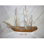 A wooden scale-built model of a three masted gun ship with deck detail and linen sails,