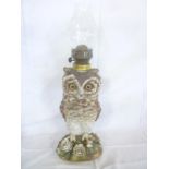 An unusual china oil lamp in the form of an owl on floral encrusted base with brass mounts and