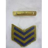 A brass First War wound stripe and backing plate together with an overseas blue cloth and khaki