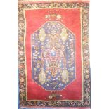 An Eastern hand knotted wool carpet with geometric and floral decoration on red ground 101" x 70"