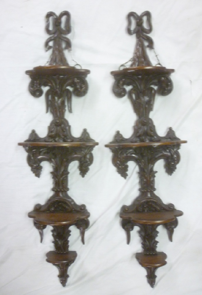 A pair of ornate Victorian carved mahogany four-tier graduated wall shelves with carved scroll