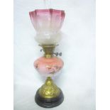 A Victorian brass oil lamp with pink opaque tinted glass floral reservoir and cranberry tinted