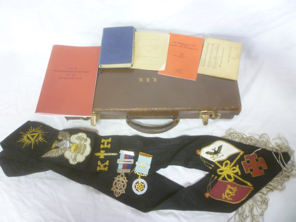 A case of various Masonic regalia including embroidered sash with eagle pendant,