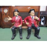 A set of Laurel and Hardy figures seated on wooden bench,