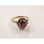 A gold ring, the central oval ruby framed by old cut diamonds, unmarked, size P, 2.