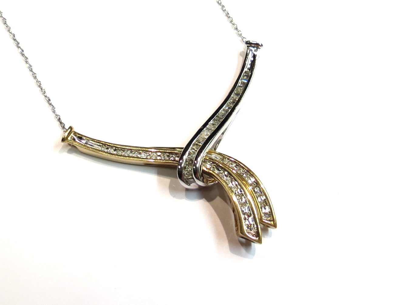 A two tone gold diamond set pendant necklace set with brilliant and baguette cut diamonds,