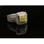 A white gold ring set with four square cut yellow diamonds framed by white diamonds in a square