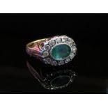 An 18ct gold emerald and diamond ring, the oval emerald in East-West setting framed by diamonds,