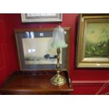 An Art Nouveau brass table lamp with a green and clear ribbed shade,