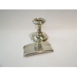 A silver ergonomic card case together with a candlestick.