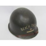 A WWII US army helmet shell with later liner bearing painted lettering "Beach Master USN" fixed
