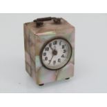 An early 20th Century mother of pearl cased miniature alarm clock, 7cm high,