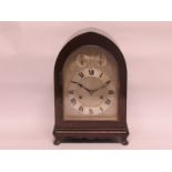 An Edwardian mahogany arch top mantel clock with silvered dial and Roman chapter ring,