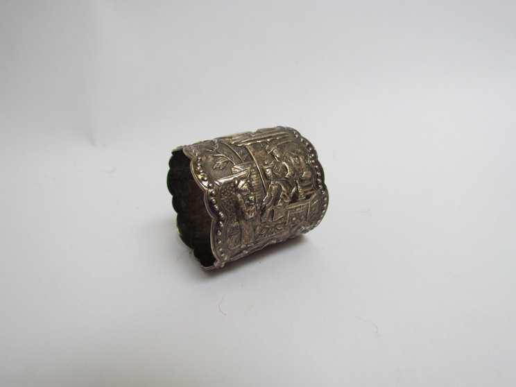 An Oriental white metal napkin ring with exterior figural scenes, 4cm tall,