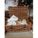 A wicker basket containing a collection of doll costume items, wigs,