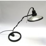 A painted black and chrome adjustable metal desk lamp on a circular cast iron base
