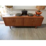 A G-Plan teak low side cabinet of four doors, shelved interiors, raised on tapering legs,