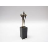 A bronze and marble sculpture of three figures joining hands, set on a marble squared plinth,