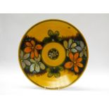 A large Poole Delphis charger with yellow ground and painted flowers in orange and turquoise,
