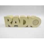 A white plastic radio in the form of the word 'RADIO'