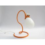 An orange table lamp with comical snake face shade