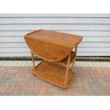 An Ercol light elm three tiered trolley with drop down sides