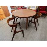 A teak circular dining table with two leaves (damaged) and four chairs (seat pads removed,