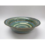 A large glazed pottery bowl painted with bands of blue, green and ochre,