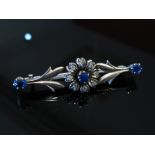 A white gold bar brooch of floral form set with sapphires and diamonds, unmarked,