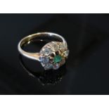 A gold diamond and emerald ring, the central emerald framed by eight old cut diamonds each .