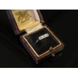 A gold ring set with three diamonds in square mounts, stamped 18ct and Plat, size N, 1.