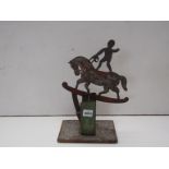 A bygone child's toy of a balancing boy on horse back,