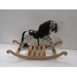 A white rocking horse with hair mane and black leather saddle