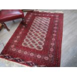 Two red ground Bokhara hand woven rugs with geometric design and tasselled ends,