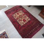 A 20th Century Iranian wool rug worked with central rectangular cream field filled with quadrant