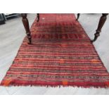 A nomadic tribal striped wool carpet worked in madder, browns and cream. 250cm x 115cm.