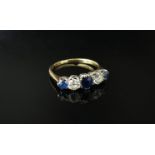 A gold five stone diamond and sapphire ring the central oval blue sapphire flanked by brilliant cut