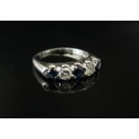 A white gold diamond and sapphire ring the central blue sapphire flanked by a diamond and sapphire