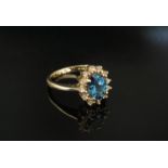 A gold ring set with oval blue centre stone framed by clear stones shank stamped 14k. Size L, 3.