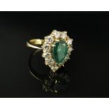 An 18ct gold ring set with central pear cut emerald, 11mm x 7mm framed by brilliant cut diamonds 1.