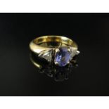 An 18ct gold ring set with central oval tanzanite flanked by trillion cut diamonds. Size N, 6.