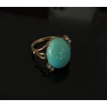 A gold ring with large cabochon turquoise flanked by two diamonds each side, stamped 750. Size P, 4.