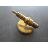 A brass spark plug paperweight
