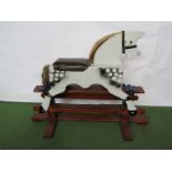 A carved and painted wooden rocking horse on trestle rocker