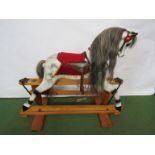 A carved painted wooden rocking horse on trestle rocker,