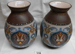 A pair of Mettlach 1829 bulbous vases in bright colours on a mainly light ground with intricate