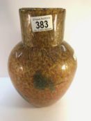 A Monart glass vase in orange, yellow and gold with blotches of green.