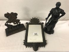 A metal figure of a blacksmith, a horse door stop and a metal framed mirror.